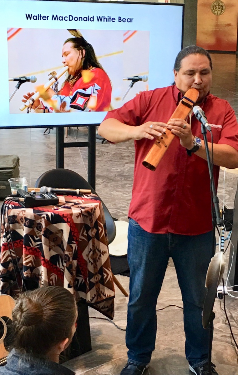 Walter playing a carved flute at a community event