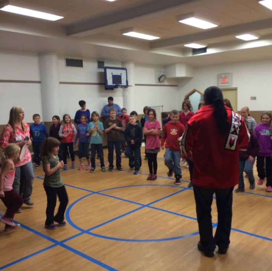 Children dancing in a circle in a school gym