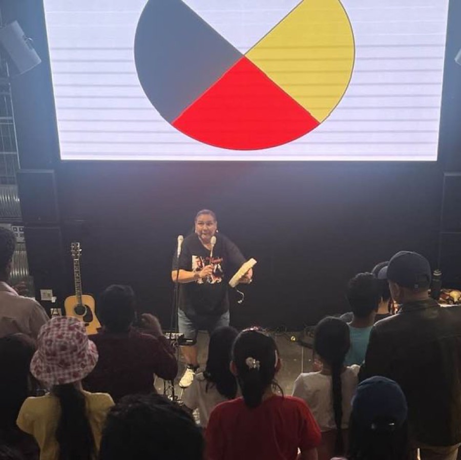 Walter performing beneath a large medicine wheel projection
